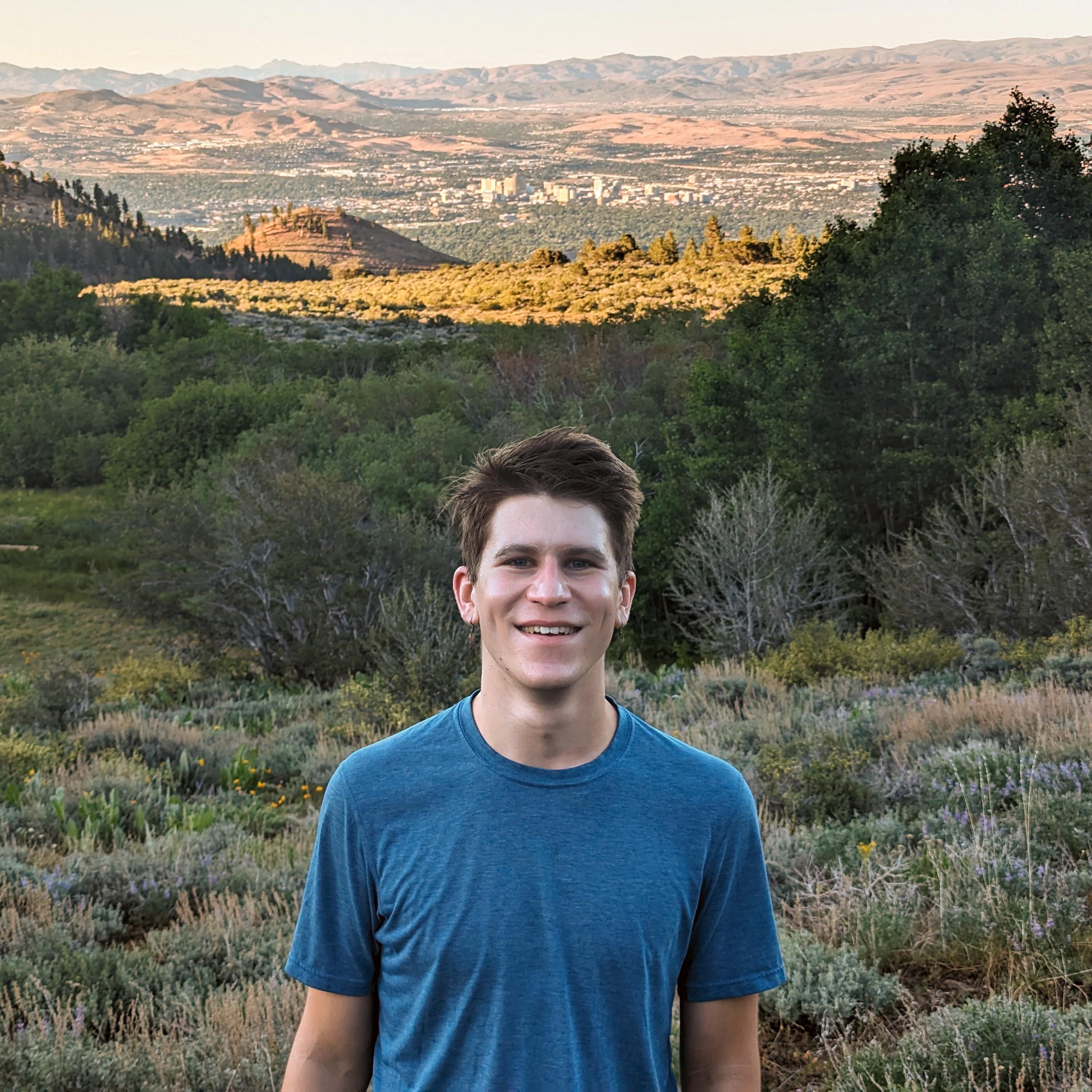 Forrest Keller looking into camera smiling while hiking Mt. Rose.